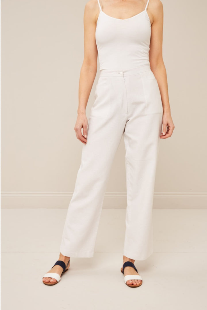Lily Ella Collection white high-waisted trousers, casual elegant style, paired with a simple strappy top and navy blue sandals, minimalist chic women's fashion.