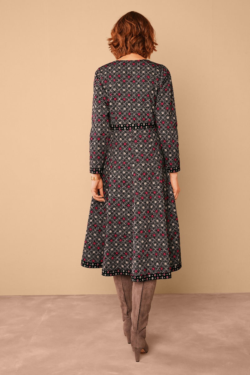 Lily Ella Collection women's black floral patterned midi dress with pink accents, three-quarter sleeves and flowy skirt paired with taupe knee-high boots, stylish autumn fashion.