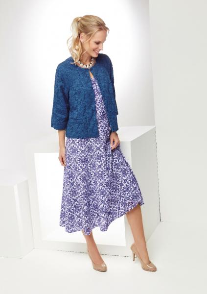 Lily Ella Collection stylish woman modeling a blue textured jacket with a purple floral patterned midi dress, elegant fashion for mature women, chic daytime look.