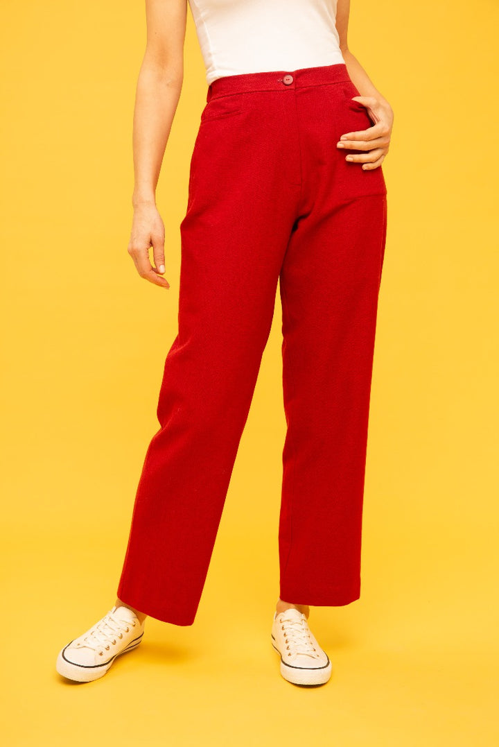 Lily Ella Collection red wide-leg trousers for women, stylish high-waisted design with button detail, paired with white sneakers on a yellow background.