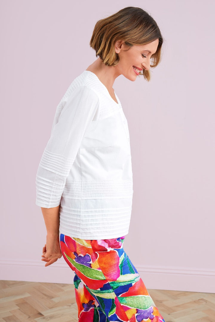 Lily Ella Collection model wearing a white pintuck blouse and colorful floral print trousers in a relaxed fit, casual spring-summer outfit idea for women.