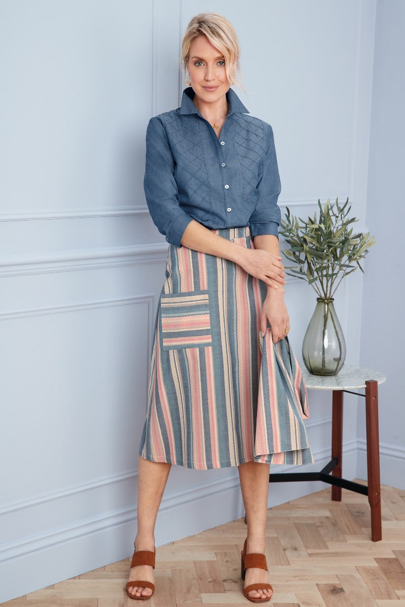 Lily Ella Collection chic blue quilted jacket paired with a colorful striped skirt, stylish women's fashion, elegant casual wear, standing pose