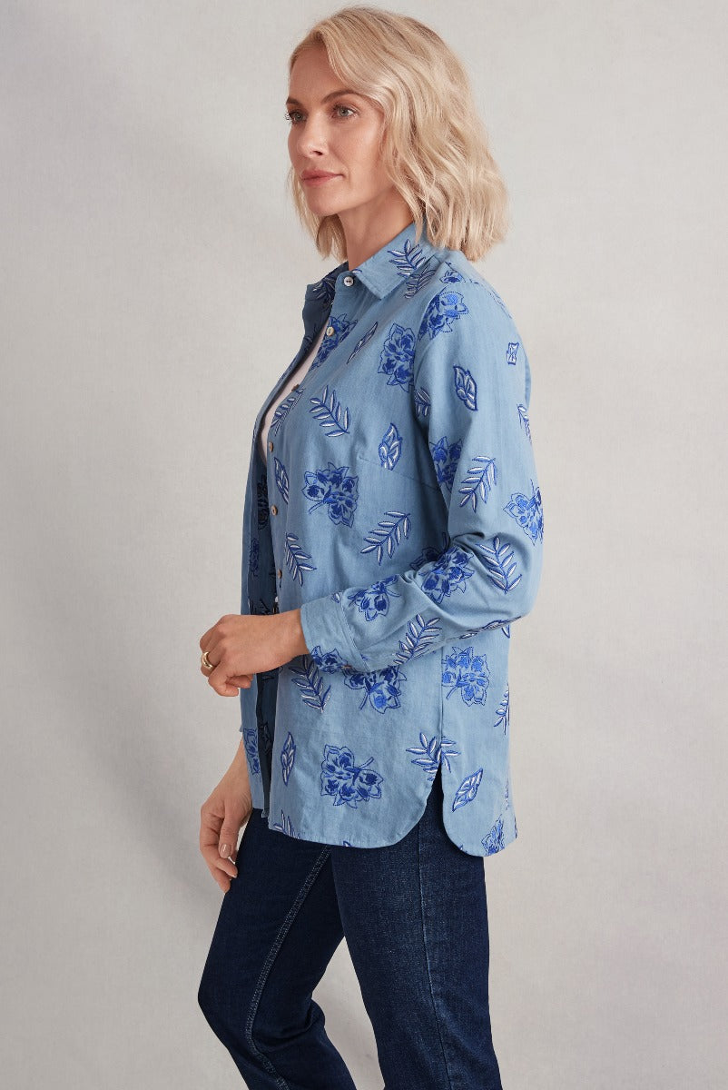 Lily Ella Collection women's blue floral patterned shirt, side view, stylish casual wear, denim jeans pairing, fashion model showcasing outfit.