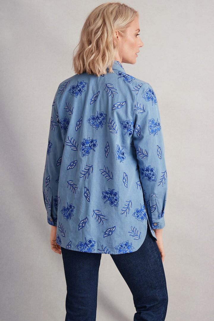 Woman in Lily Ella Collection blue floral patterned chambray shirt, styled with dark denim jeans, casual chic women's Spring fashion, contemporary design, rear view showing garment fit and print detail.