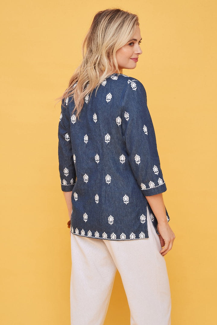 Lily Ella Collection navy blue floral print tunic top with three-quarter sleeves styled with white linen trousers on a model against yellow background