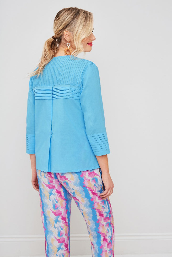 Lily Ella Collection sky blue cardigan with pleat back detail paired with colorful floral print trousers, stylish women's fashion, rear view.
