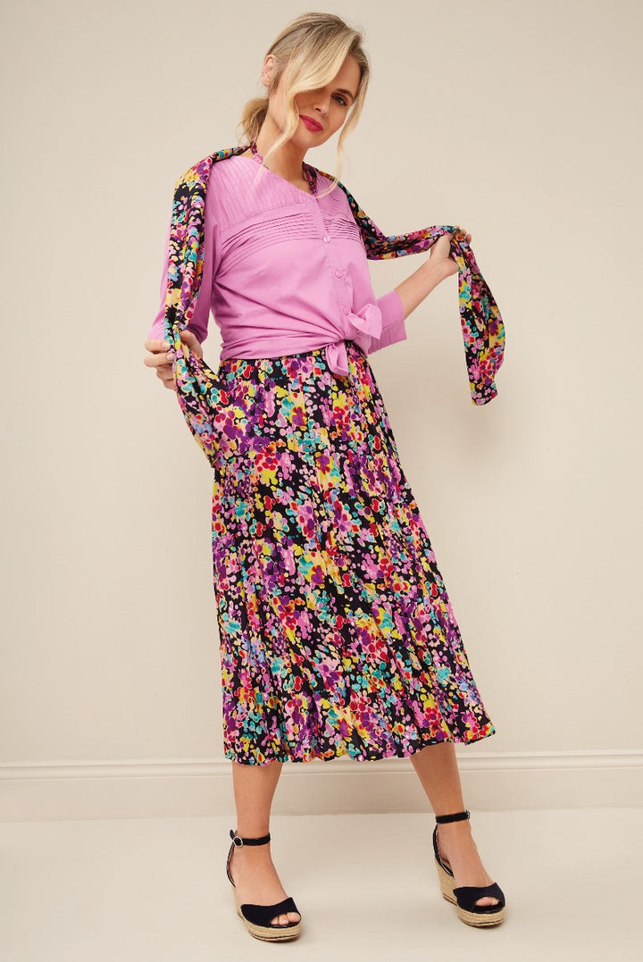 Lily Ella Collection - Model in vibrant pink blouse and colorful floral mid-length skirt with black ankle-strap espadrilles, showcasing contemporary women's fashion and elegant casual wear.