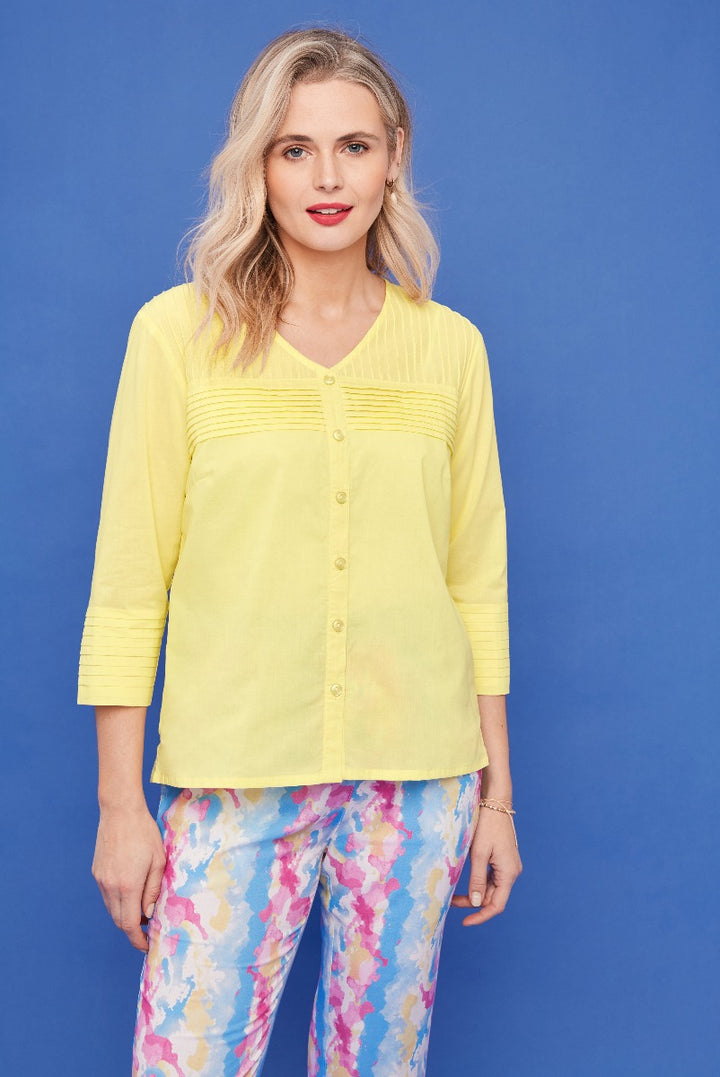 Lily Ella Collection yellow pin-tuck blouse with three-quarter sleeves paired with colorful floral pattern trousers, stylish women's casual wear against a blue background.