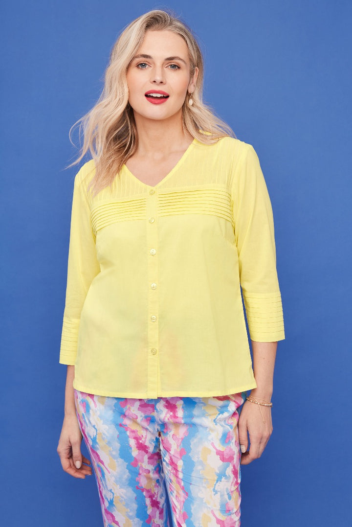 Lily Ella Collection yellow blouse with pintuck detailing and 3/4 sleeves paired with colorful abstract print trousers, stylish women's spring fashion outfit.