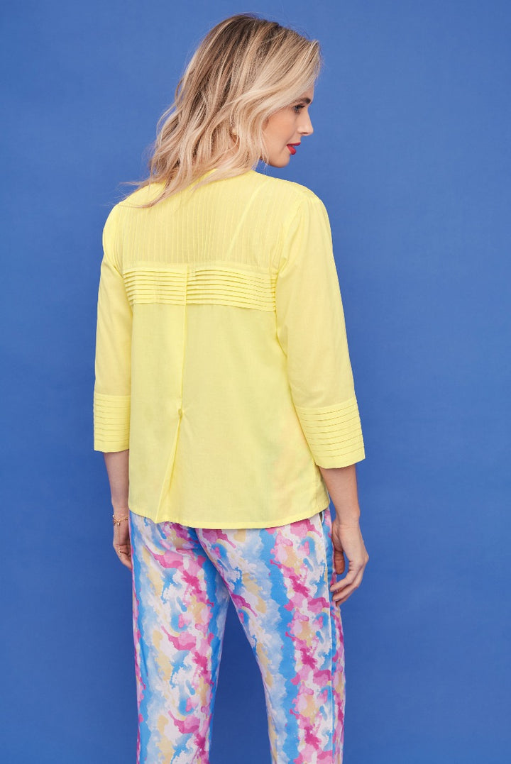 Lily Ella Collection yellow pleated back detail blouse paired with colorful floral print trousers, women's fashion clothing, stylish spring outfit idea, rear view on blue background