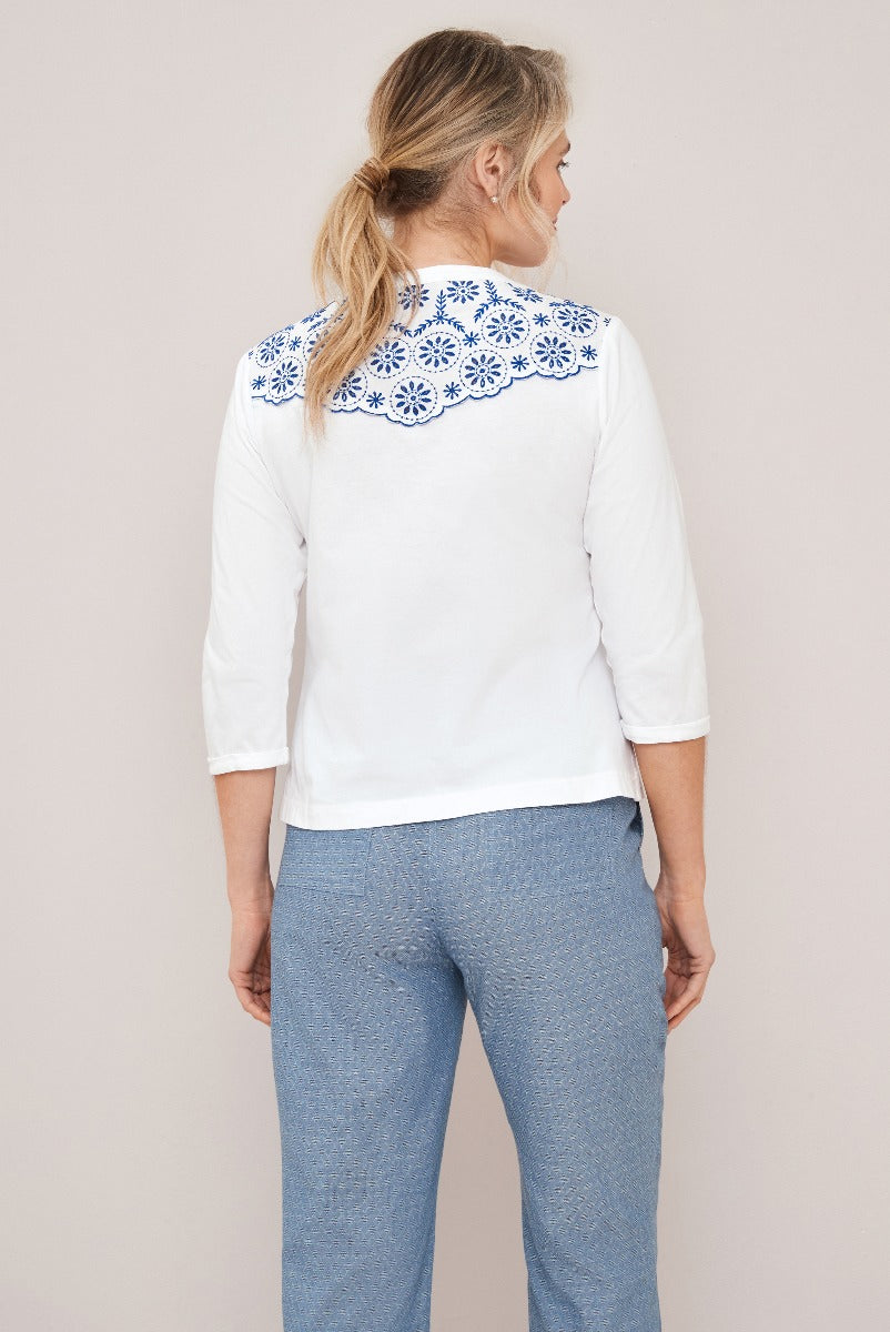 Lily Ella Collection white blouse with blue embroidered detailing on collar and denim-style trousers, featuring women's contemporary casual fashion.