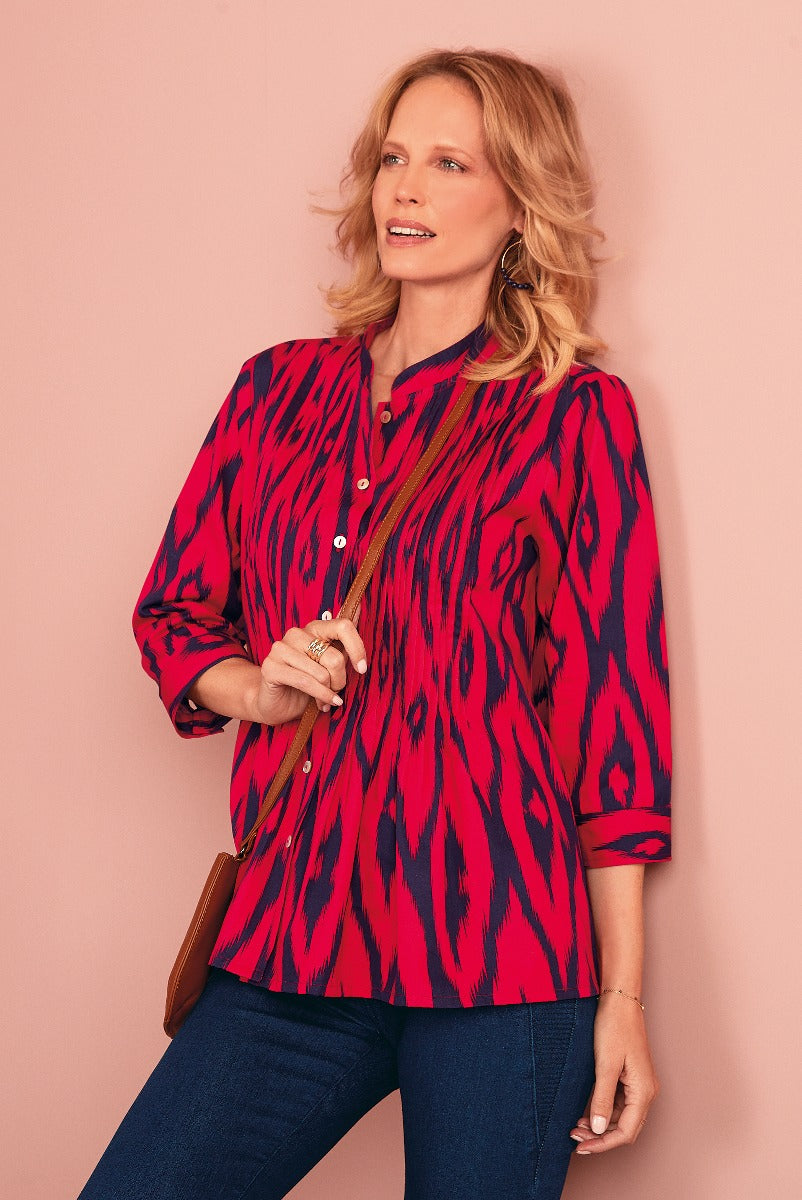Lily Ella Collection red and black animal print tunic blouse for women, casual chic three-quarter sleeve top paired with jeans and accessorized with gold earrings and crossbody bag