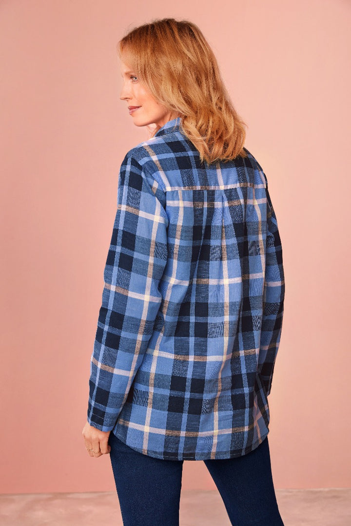 Lily Ella Collection stylish blue plaid oversized shirt with a casual fit modelled by a woman against a pink background, paired with dark denim jeans for a modern look.
