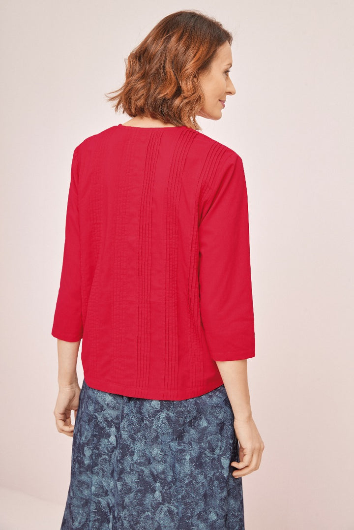 Lily Ella Collection red pleated-back blouse with 3/4 sleeves paired with a floral patterned navy skirt, stylish comfortable women's apparel, rear view