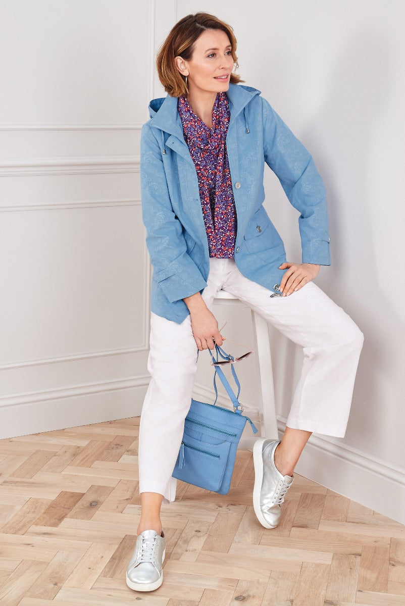 Lily Ella Collection sky blue casual jacket paired with white trousers and printed blouse, accessorized with a blue tote bag and metallic silver sneakers, stylish women's spring outfit idea