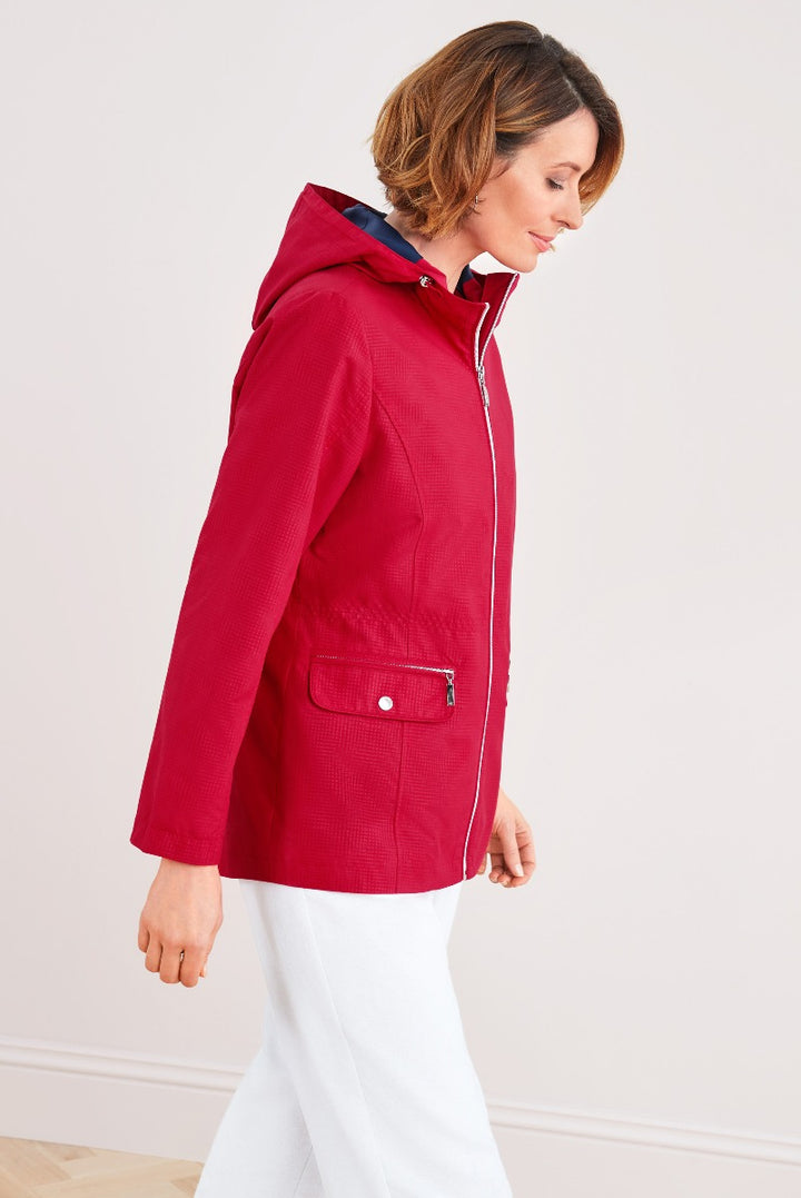 Lily Ella Collection red hooded jacket with contrast navy lining for women, stylish outerwear, side view showing pocket detail and zip, teamed with white trousers