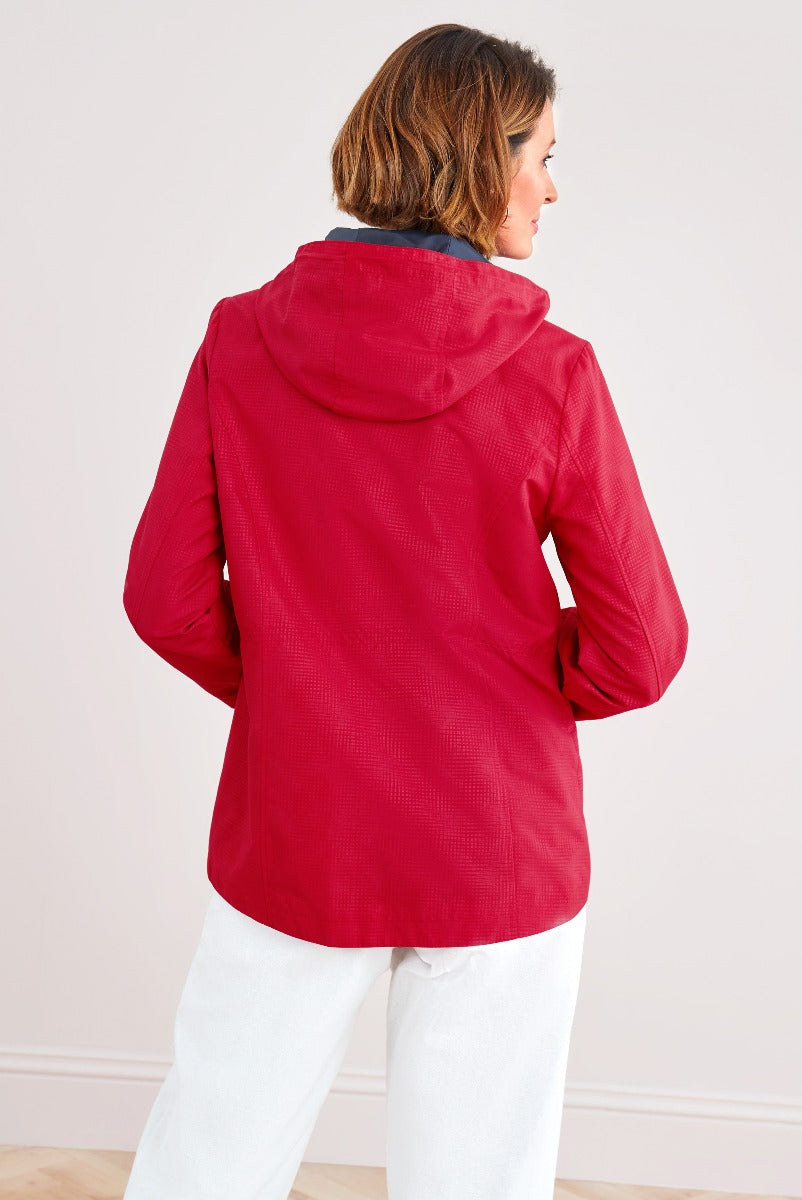 Lily Ella Collection red hooded jacket, casual style, women's spring outerwear, model showcasing back view with contrast lining, paired with white trousers.