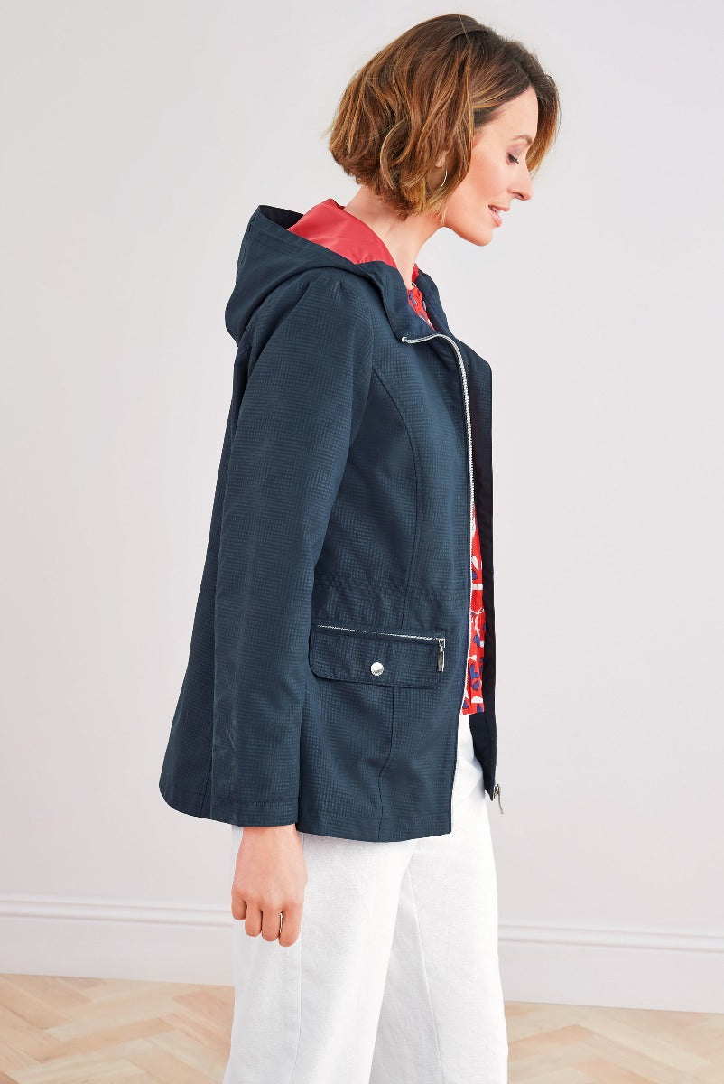 Lily Ella Collection navy blue casual jacket with hood and red lining, stylish women's outerwear, side profile view with white trousers.