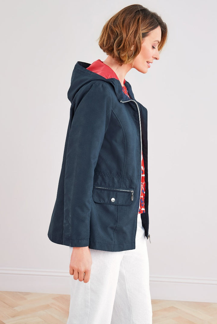 Side view of a woman wearing a Lily Ella Collection navy blue textured jacket with a contrasting red inner lining, styled over white trousers for a casual chic look.
