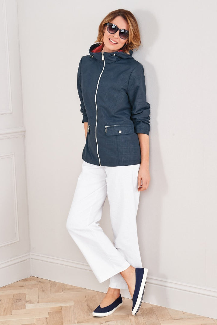 Lily Ella Collection stylish navy blue casual jacket with white trim paired with white trousers and comfortable slip-on shoes, fashionable women's apparel, model showcasing chic outerwear and relaxed pants with a sophisticated yet casual appearance.