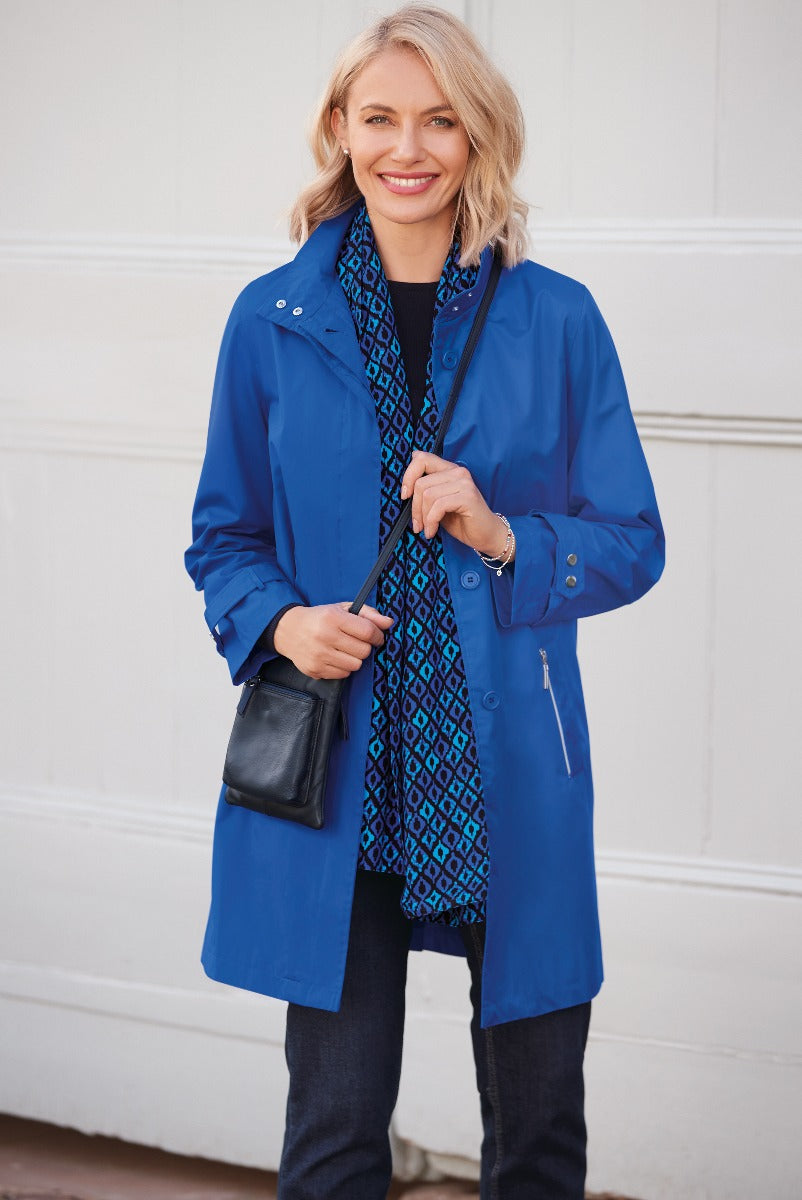 Lily Ella Collection elegant cobalt blue raincoat, stylish waterproof outerwear for women, model pairing with patterned blouse and denim, casual chic look, fashion-forward design with comfortable fit