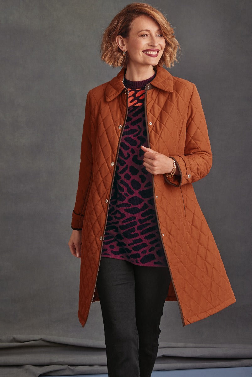 Lily Ella Collection stylish burnt orange quilted coat with patterned sweater and black pants, elegant casual women’s autumn fashion.