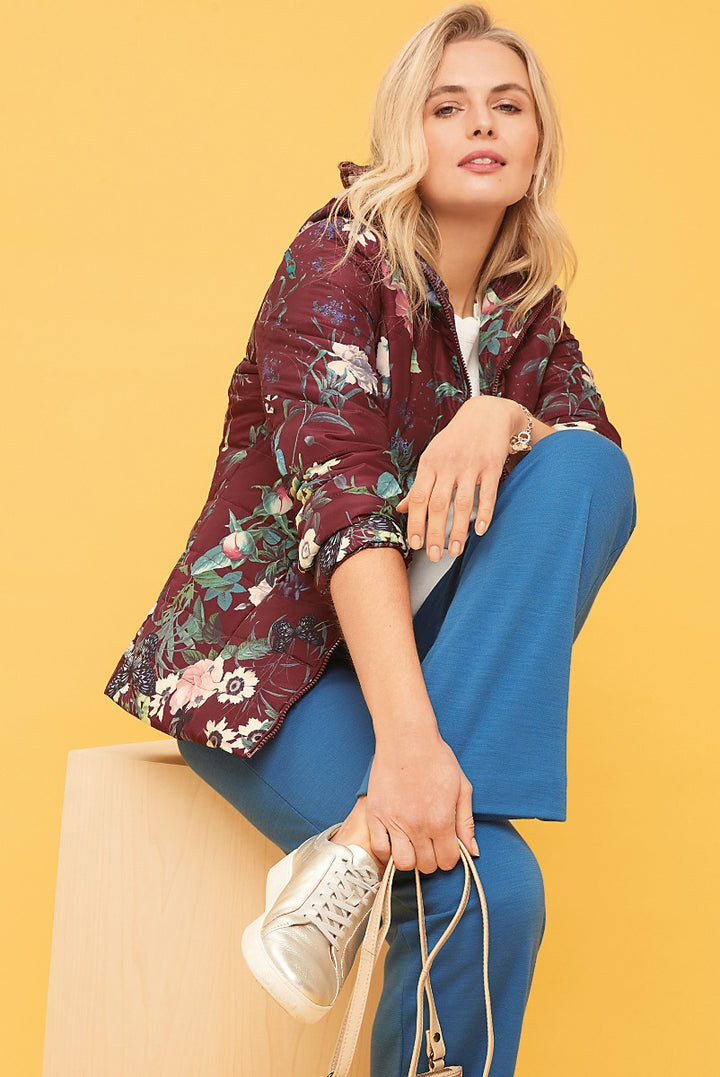 Lily Ella Collection maroon floral bomber jacket and blue trousers on model against yellow background