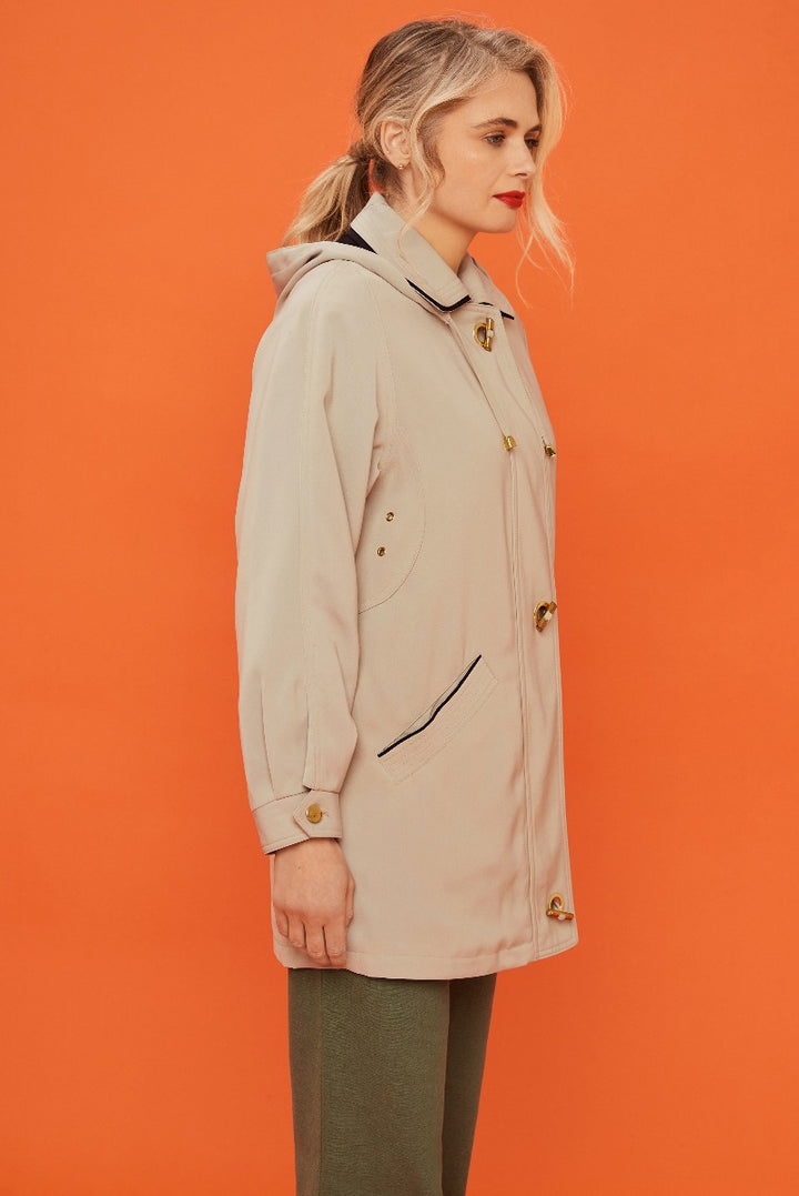 Lily Ella Collection beige trench coat, classic style, woman modeling spring outerwear, elegant design, against orange background