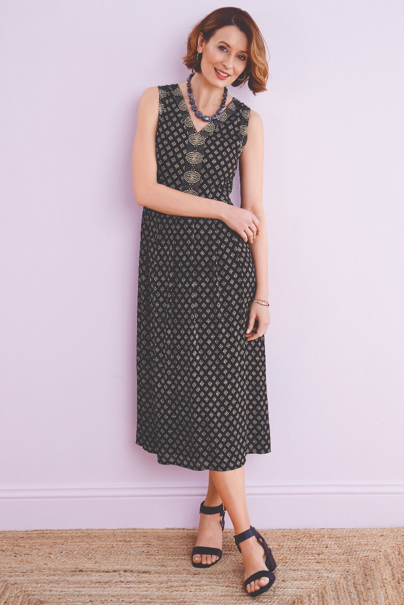 Lily Ella Collection elegant black patterned mid-length sleeveless dress styled with coordinating necklace and black strappy sandals, perfect for sophisticated ladies' fashion