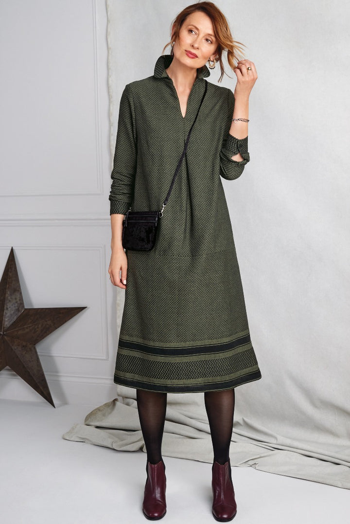 Lily Ella Collection elegant women's olive green geometric print shirt dress with black detailing, styled with opaque tights and maroon ankle boots, trendy fashion for modern sophisticated look.