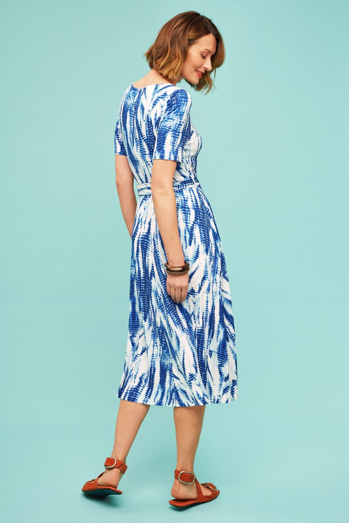 Lily Ella Collection blue and white tie-dye pattern midi dress with short sleeves and cinched waist, paired with tan sandals on pastel background.
