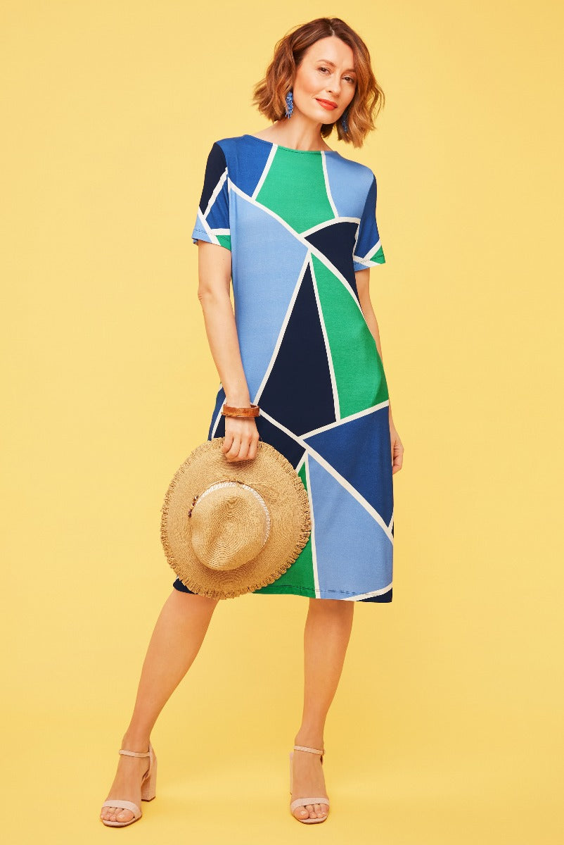 Lily Ella Collection geometric pattern dress in blue, green, and white, stylish summer outfit with straw hat and beige heels, elegant women's fashion.