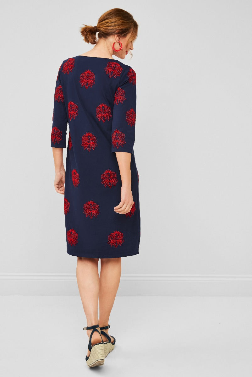Lily Ella Collection navy blue midi dress with red floral pattern, elegant 3/4 sleeve design, woman modeling stylish apparel with wedge heels and matching red earrings