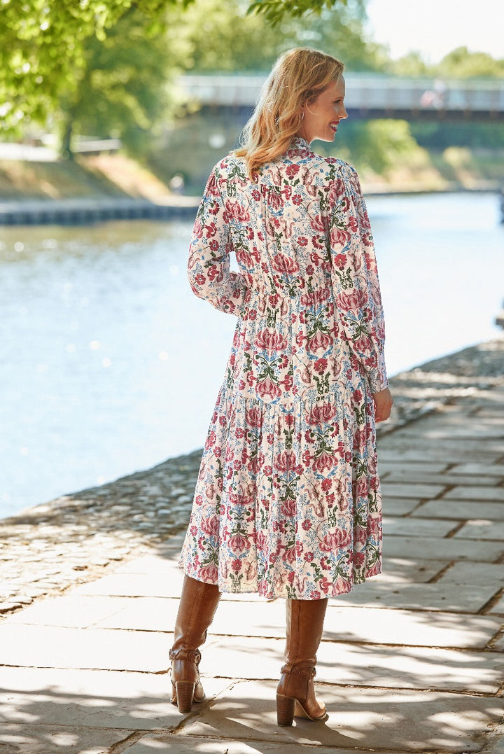 Lily Ella Collection floral print midi dress in pastel shades with elegant full sleeves and tiered skirt, paired with brown leather boots, outdoor riverside setting