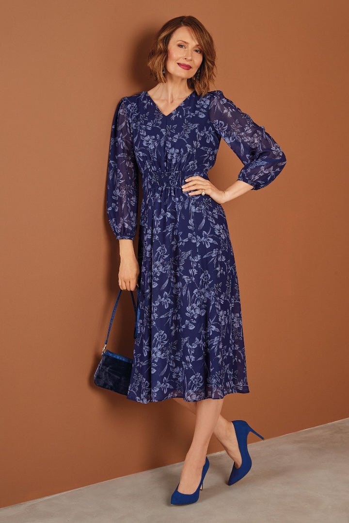 Lily Ella Collection elegant navy blue floral midi dress with sheer sleeves paired with blue velvet high heels and matching shoulder bag for a sophisticated women's fashion look.