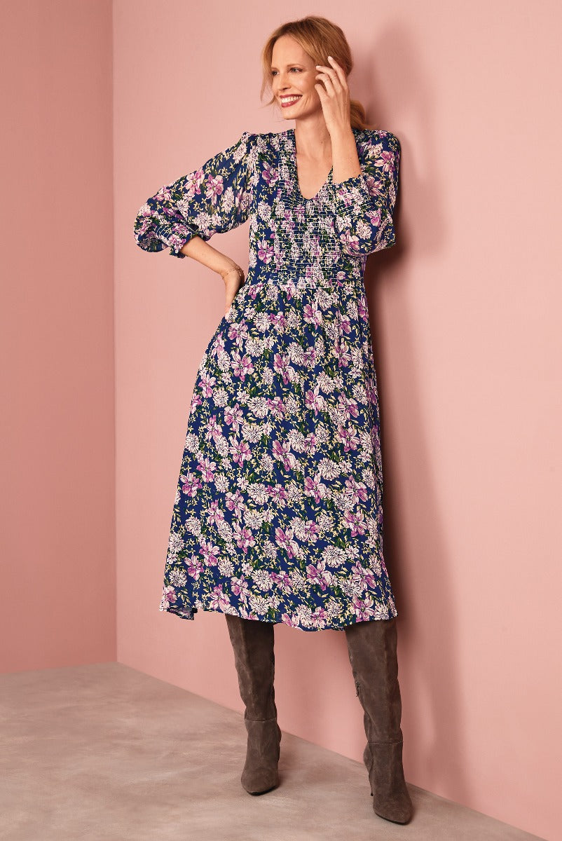 Lily Ella Collection navy blue floral mid-length dress with three-quarter sleeves and v-neckline paired with taupe knee-high boots, stylish women's autumn fashion.