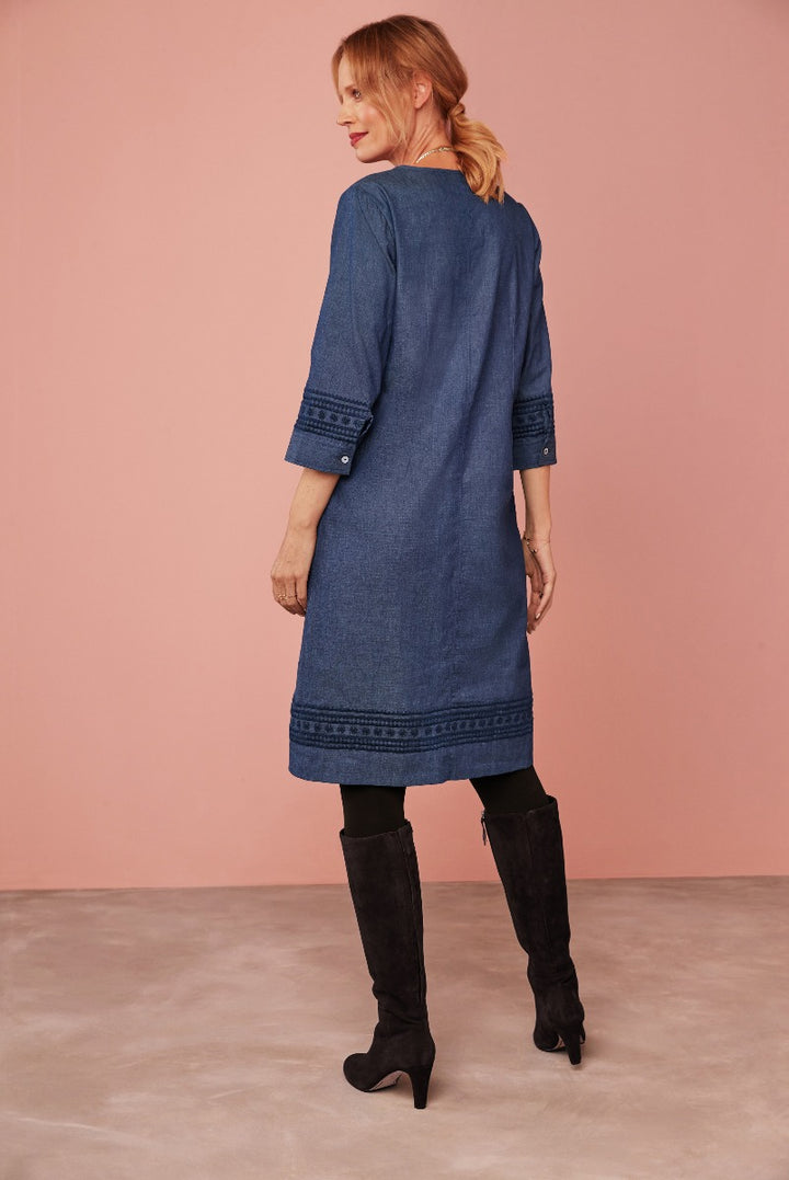 Lily Ella Collection stylish denim blue tunic dress with embroidered sleeve detail paired with black knee-high boots on model, elegant casual wear for women.