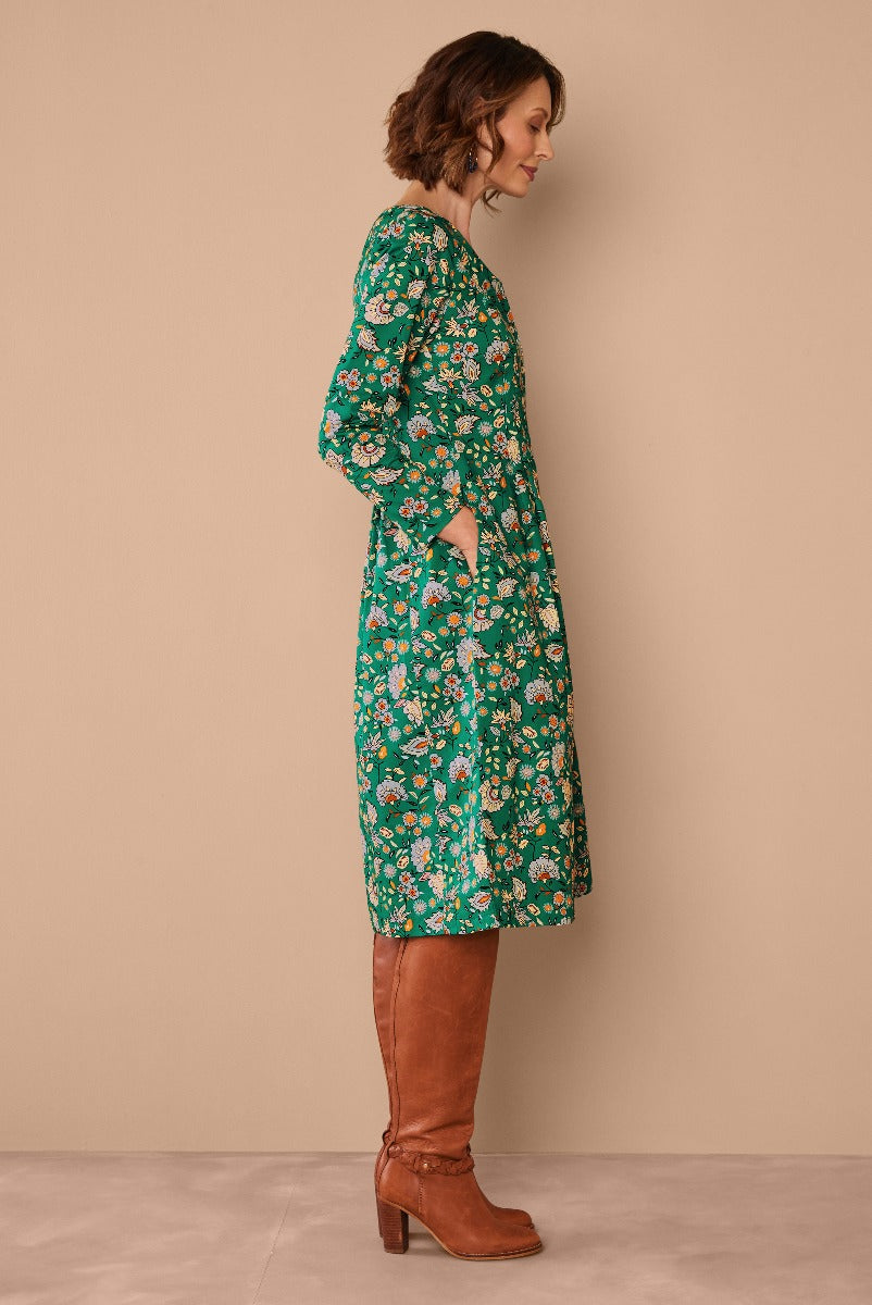 Lily Ella Collection green floral mid-length dress with side pockets paired with brown leather boots, showcasing casual elegance and contemporary women's fashion.