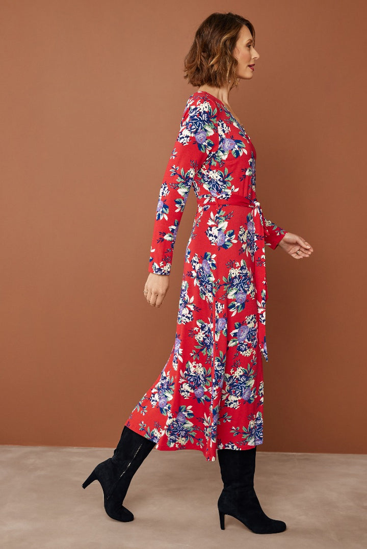 Lily Ella Collection red floral midi dress with long sleeves and black ankle boots on model against warm background