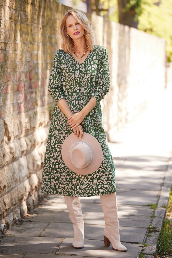 Lily Ella Collection elegant green floral midi dress with V-neck and long sleeves paired with beige knee-high boots and a light pink hat for a stylish spring outfit.