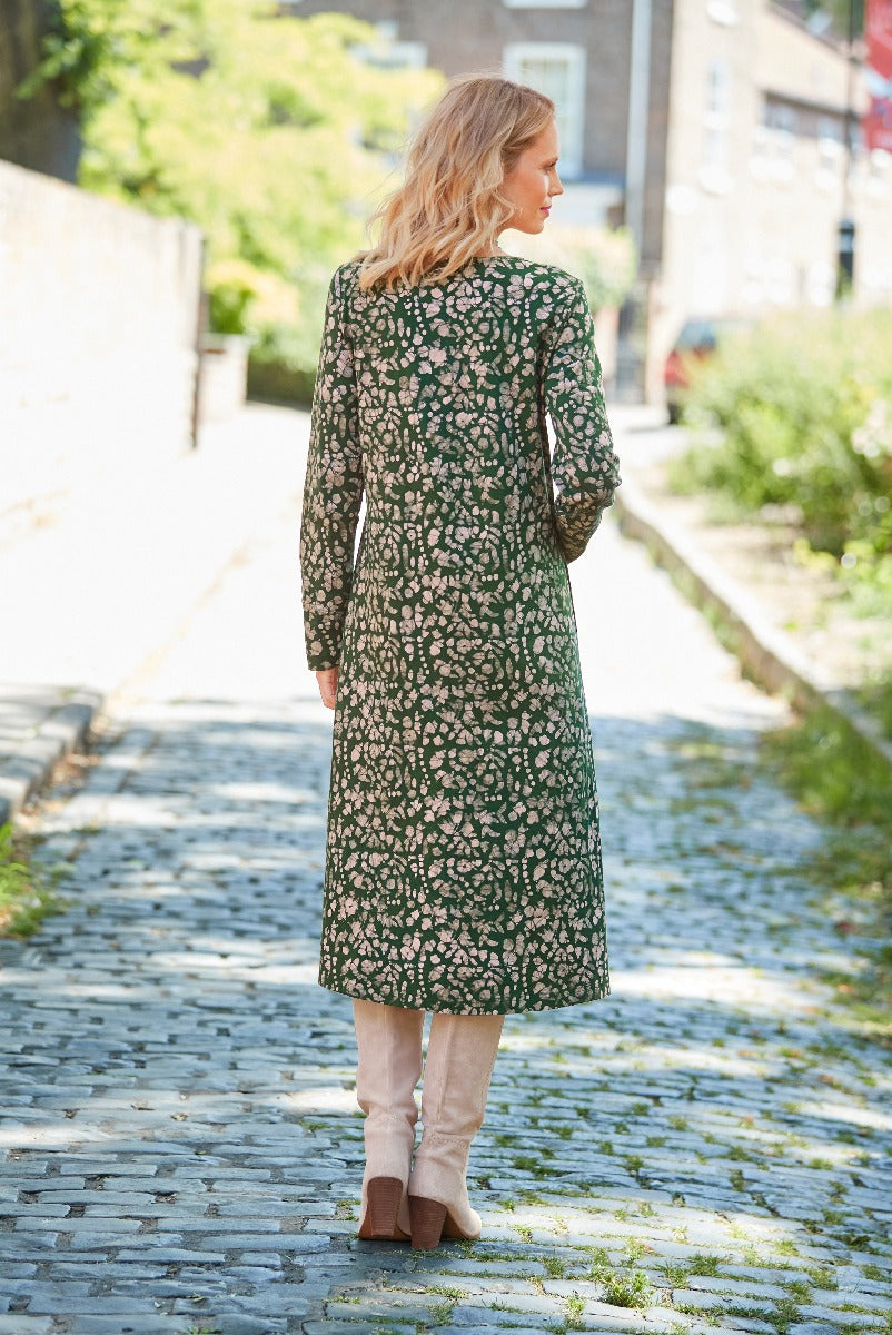 Lily Ella Collection green floral midi dress, woman walking in stylish autumn attire, pairing with beige boots, elegant casual wear for women.