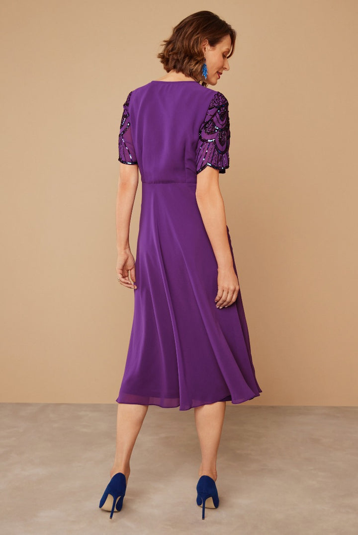 Lily Ella Collection elegant purple midi dress with embellished sleeves and matching blue heels, featuring a feminine A-line cut and sophisticated style for evening wear.