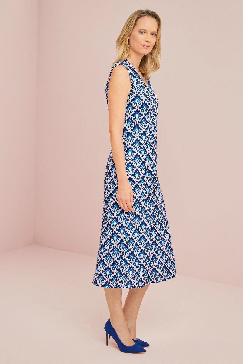 Lily Ella Collection blue and white patterned sleeveless midi dress with matching blue high heels on model against pink background