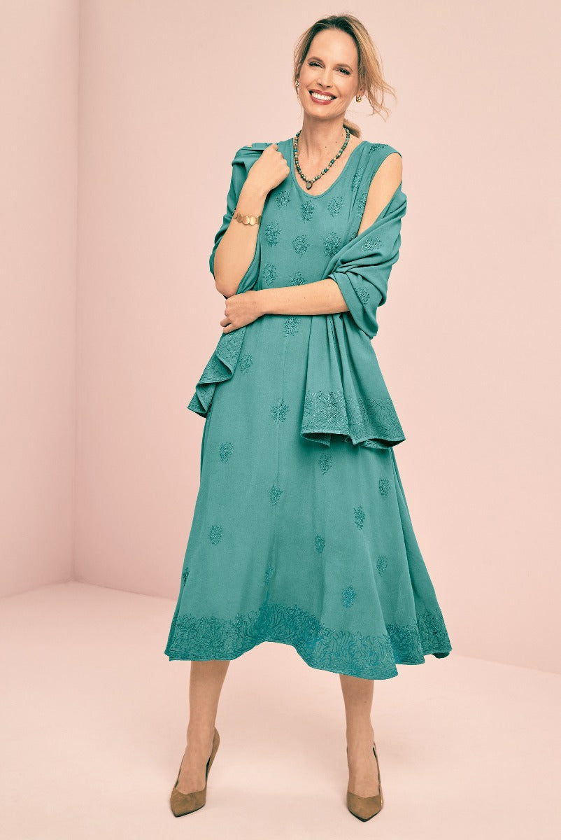 Lily Ella Collection teal embroidered mid-length dress with sheer sleeves and scalloped hem, paired with elegant accessories for a sophisticated look