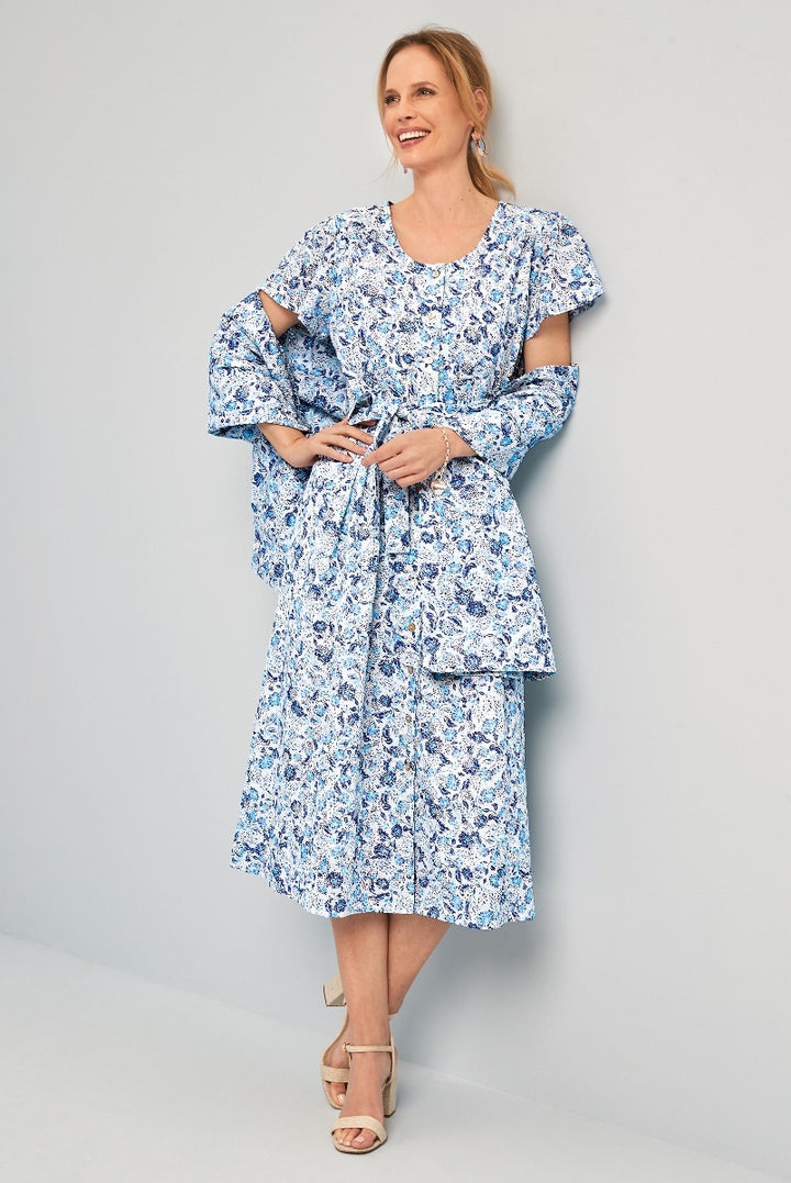 Lily Ella Collection blue floral patterned tiered dress with ruffle sleeves and tie waist on smiling model paired with beige heeled sandals