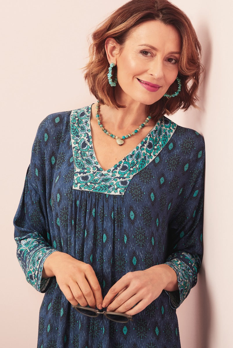 Lily Ella Collection teal bohemian-style dress with intricate patterns, featuring a woman modeling with coordinating turquoise jewelry, highlighting the brand's elegant and casual fashion line.