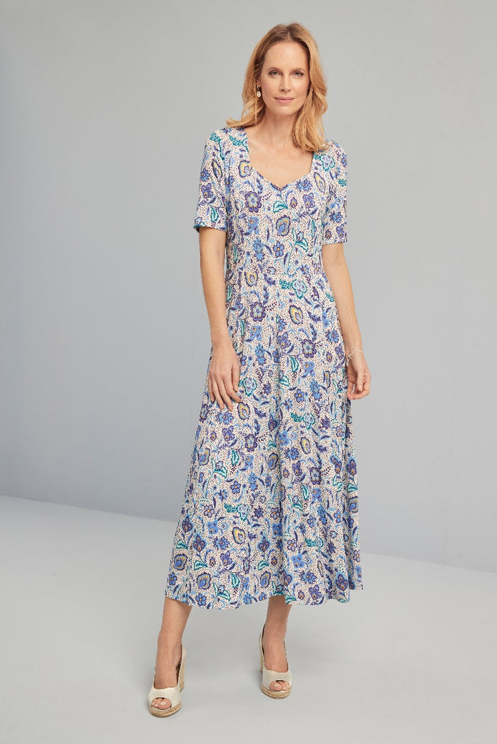 Lily Ella Collection blue paisley print midi dress with short sleeves, elegant v-neck style, and flowing skirt modeled with beige open-toe heels.