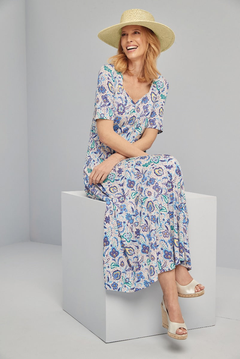 Lily Ella Collection stylish blue and white floral patterned maxi dress with short sleeves and v-neck design, accessorized with a wide-brim straw hat and white wedge sandals, perfect for summer fashion.