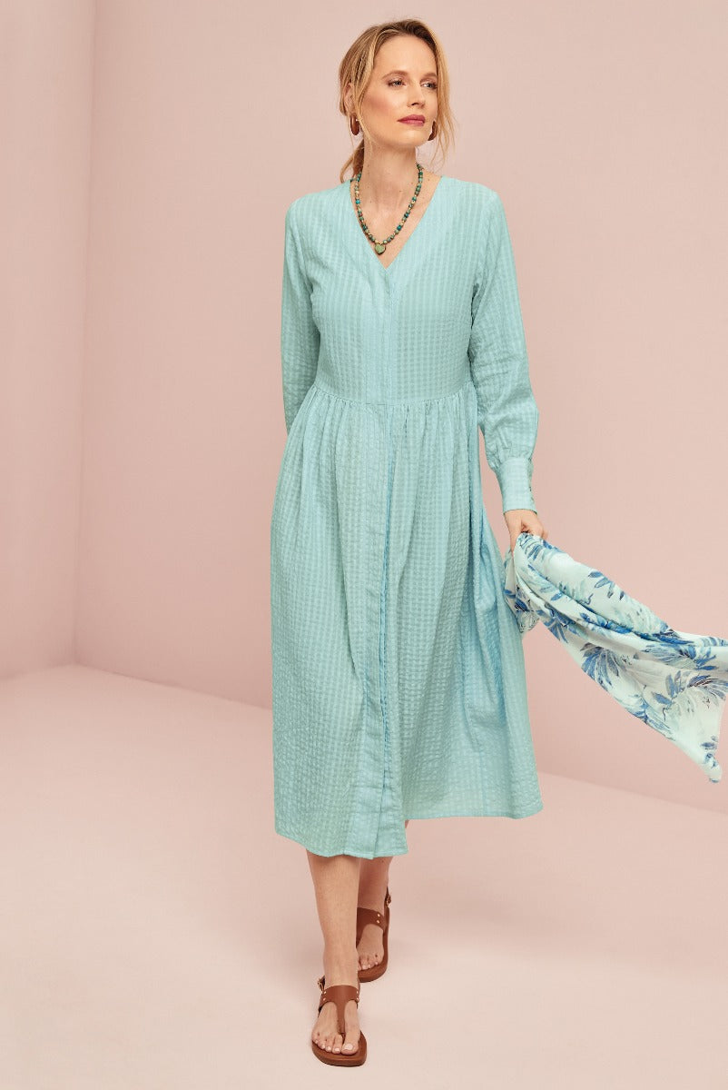 Lily Ella Collection light blue textured maxi dress with V-neck and long sleeves for women, paired with a floral blue scarf and brown sandals, showcasing elegant casual spring fashion.