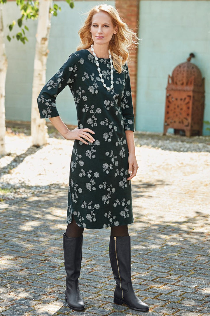 Lily Ella Collection elegant black floral print dress with three-quarter sleeves paired with tall black leather boots and statement white necklace for a sophisticated outfit.